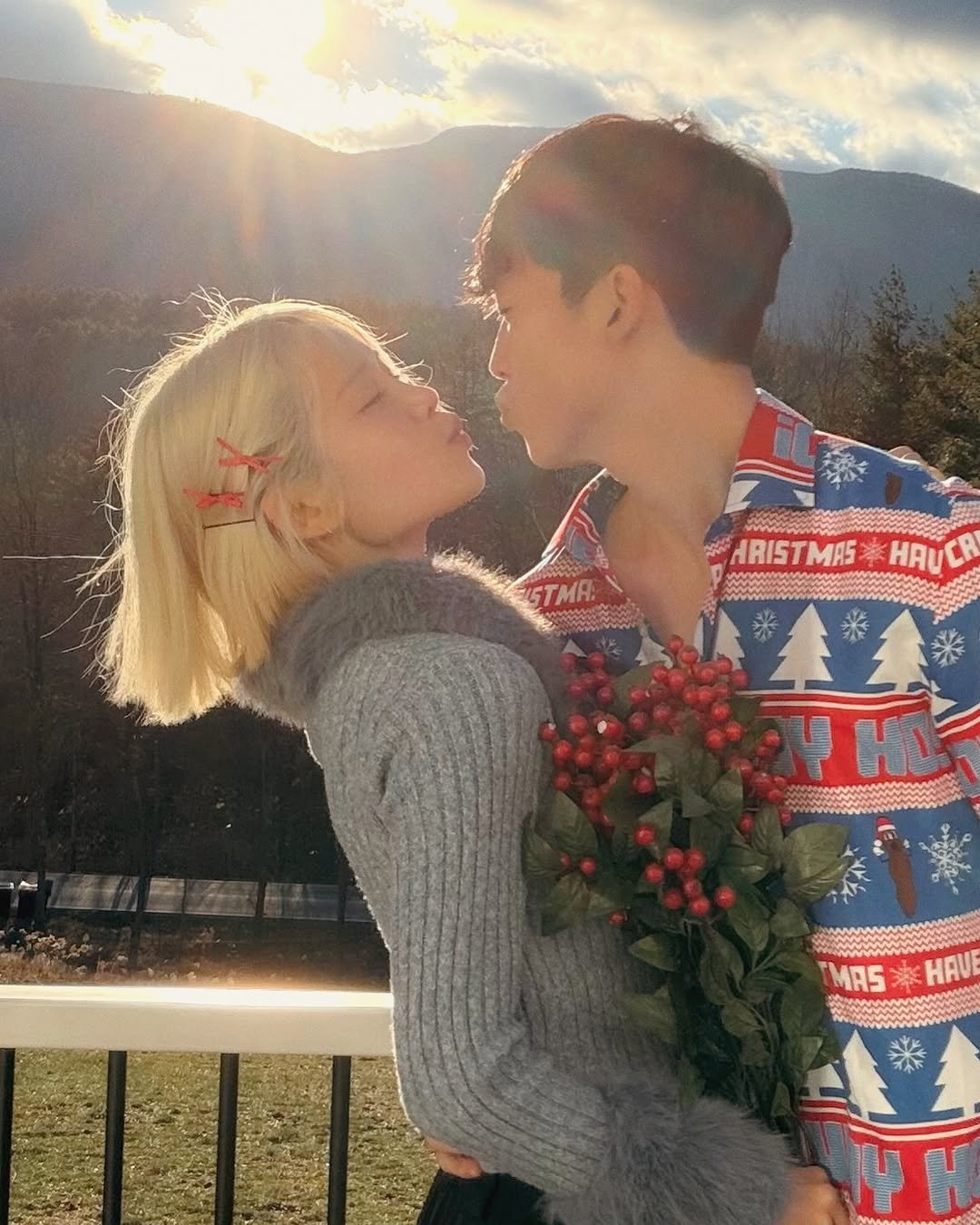 Photo by Mina 미나 on December 26, 2025. May be an image of one or more people, blonde hair, people kissing, christmas tree, sweater and text.