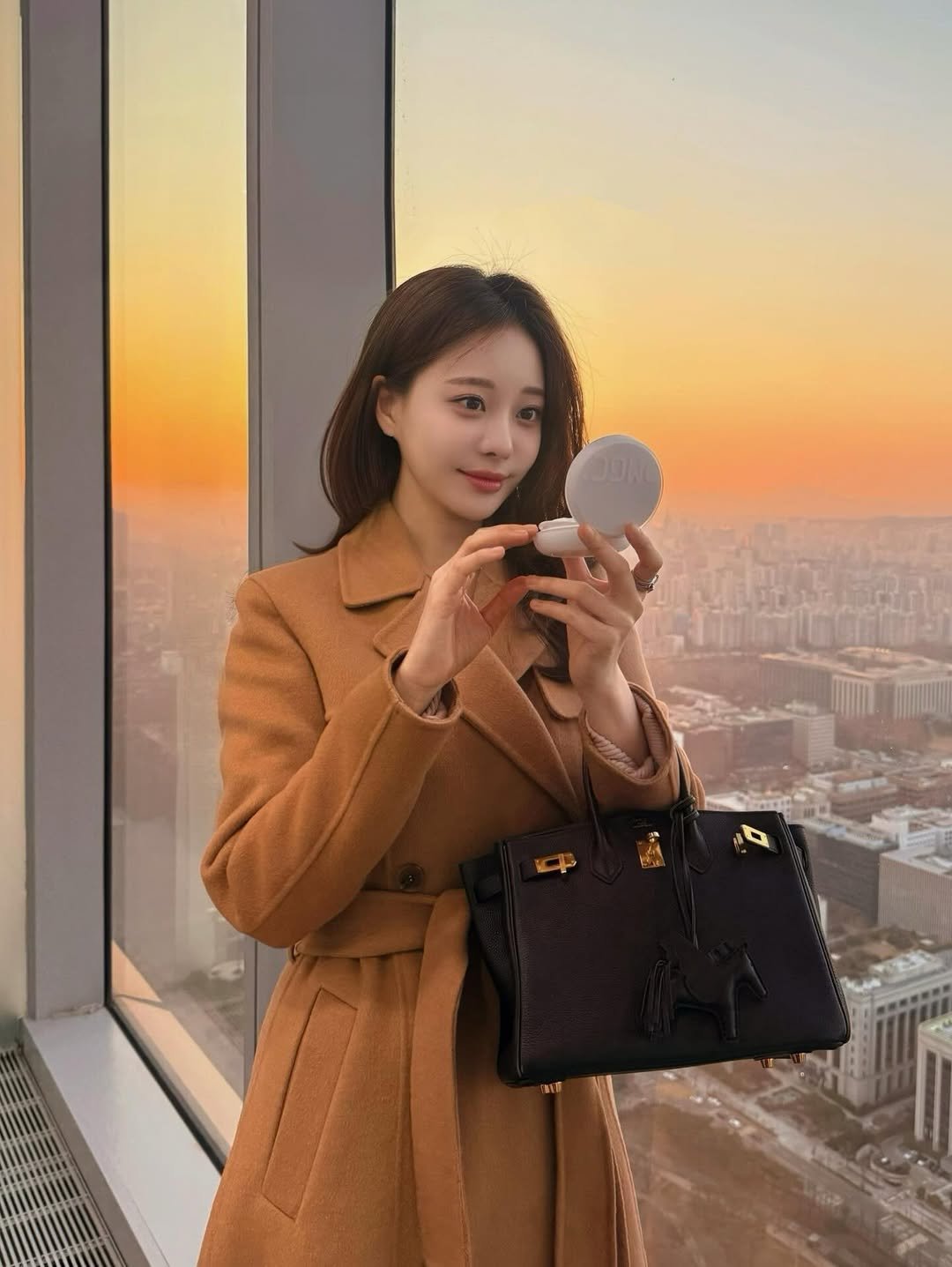 Photo by 김민영🌸아옳이 on December 19, 2025. May be an image of overcoat, duffle coat, phone, purse, Victoria Peak and text.