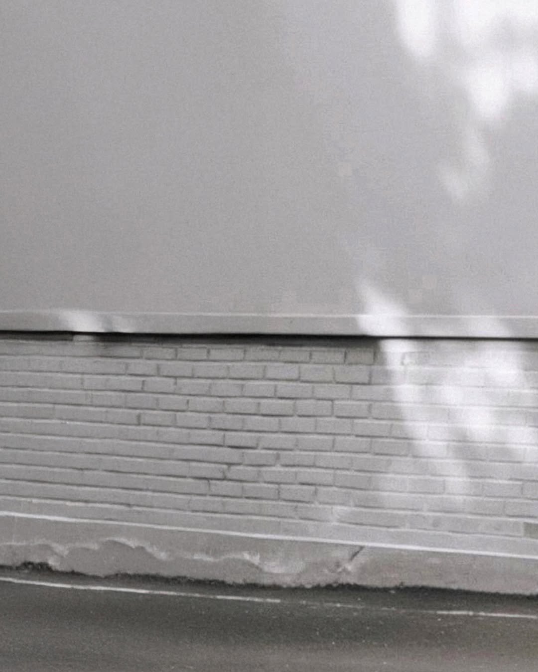 Photo by MMIC (엠엠아이씨) on February 08, 2026. May be a black-and-white image of brick wall, curb and text.