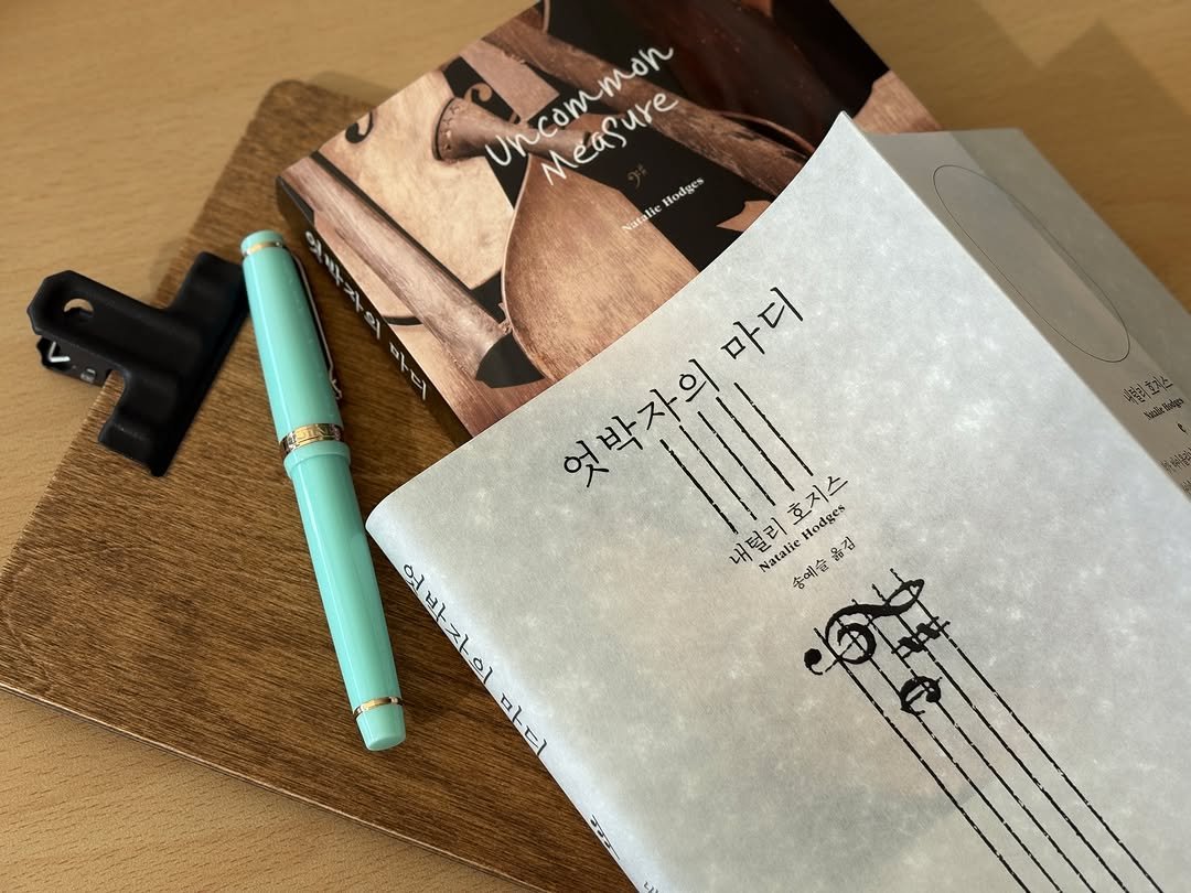 Photo by 문학동네 공식 인스타그램 on November 16, 2025. May be an image of ‎diary, book, musical instrument, pen, binder, clipboard and ‎text that says '‎a OΑ-ΣOικAAΝ Uncommon Measure ure Hodges Natalie lie aL 마디 엇박자의 III 내털리호지스 내택 ㅐ털리 호지스 Hodges 언박자의 ۵ه Natalie 송예술율 김 바자이 ١٥١ ER 마디 al atel သသသ‎'‎‎.