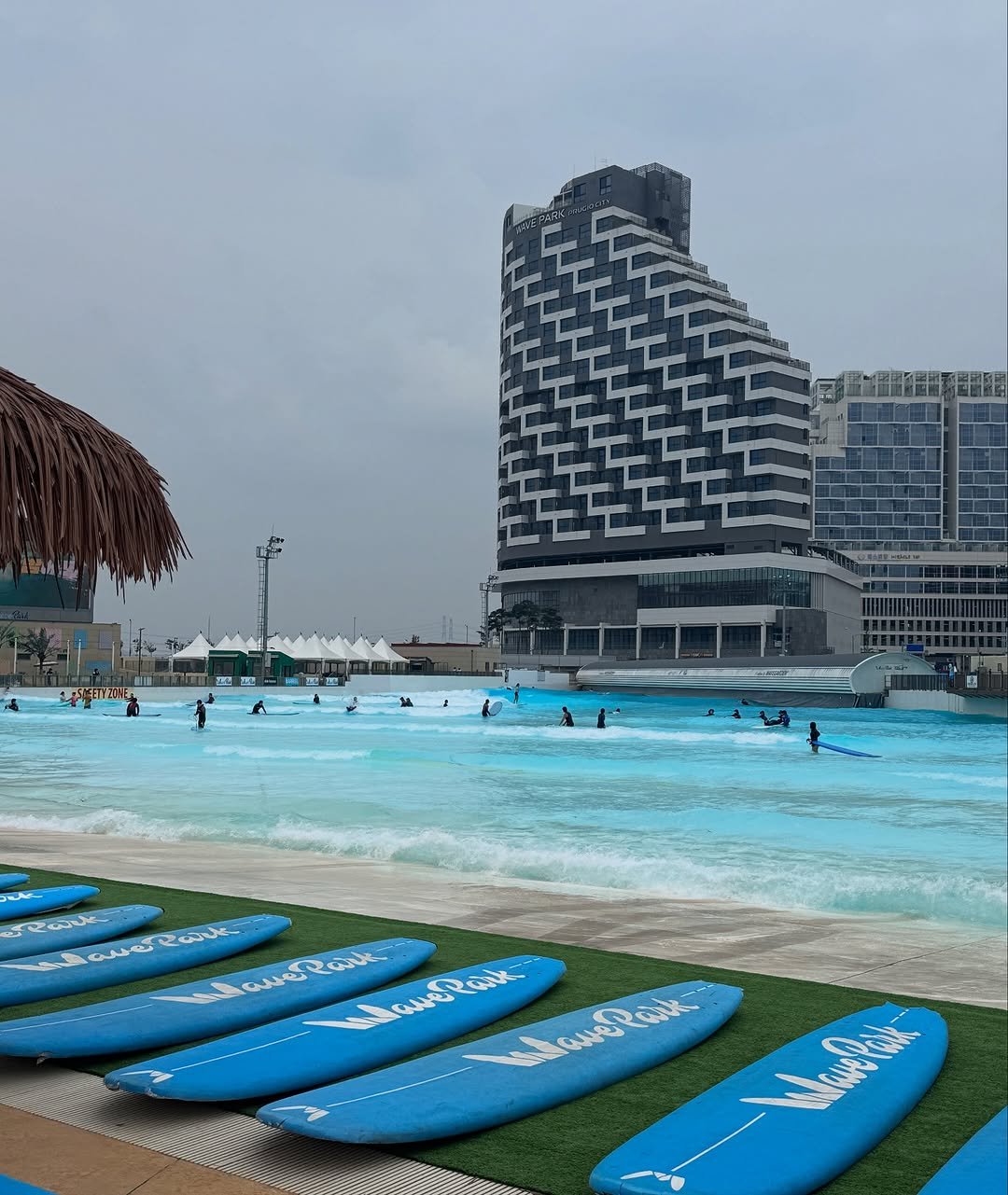 Photo by 내맘코 on August 10, 2025. May be an image of 6 people, surfboard, deck chair, skyscraper, pool, water, tower, buildings and text.