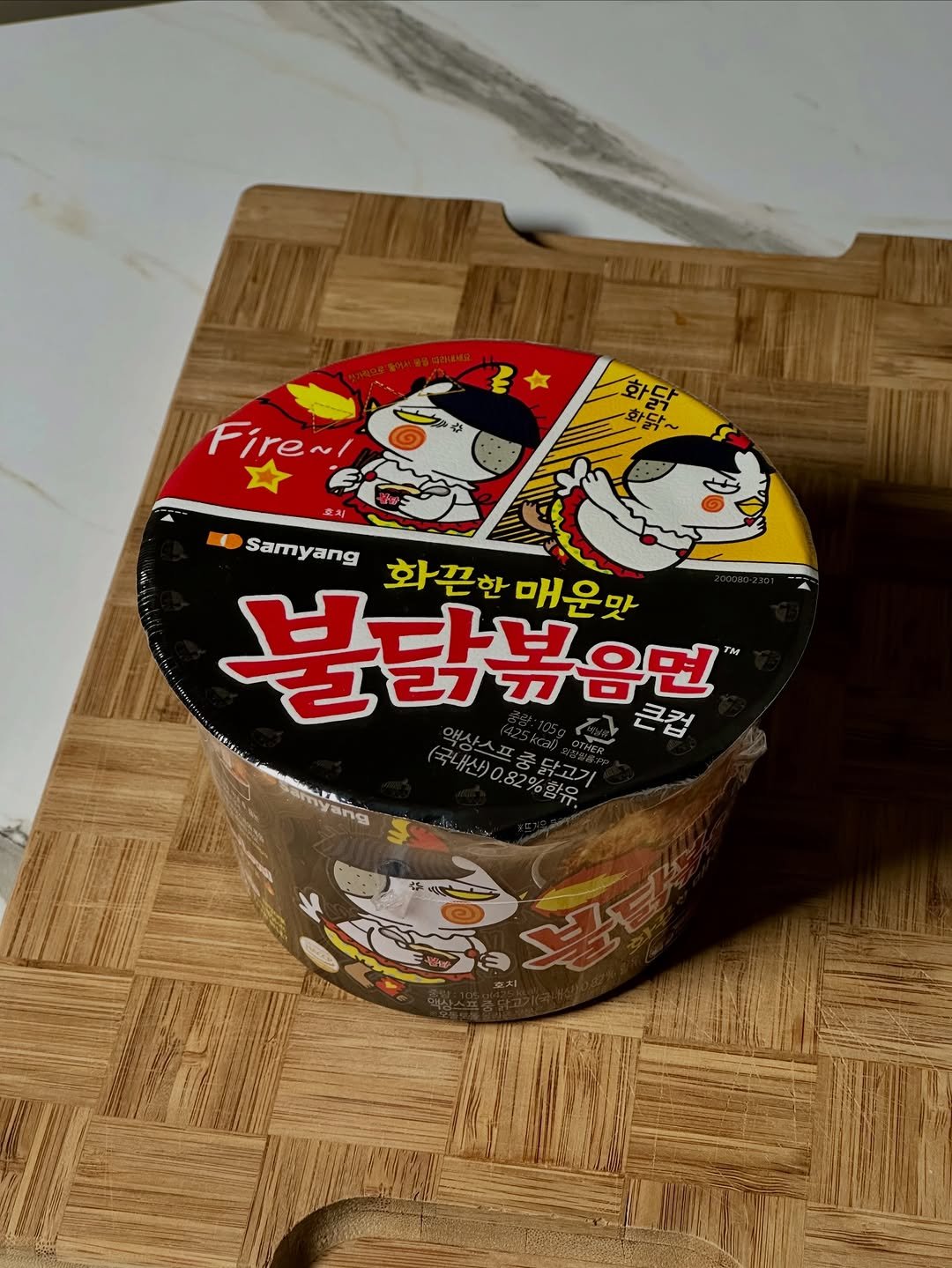 Photo by NamCook 남쿡 on January 02, 2026. May be an image of food and text that says '화 화당 화담~ 닦~ Fire~ मै ME Samyang 화끈한매운맛 화끈한 매운맛 불닭볶음면 TM 큰컵 (국내산)0.82%함유. ㅋ상스프중닭고기 ynnyA Bng'.