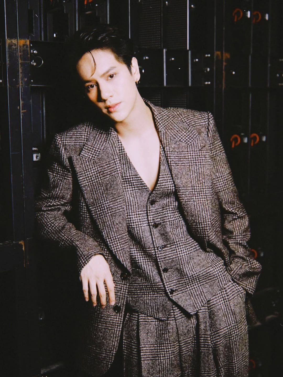 Photo shared by NANON on November 28, 2025 tagging @dolcegabbana. May be an image of one or more people, makeup, overcoat, suit, blazer, bolo tie and text.