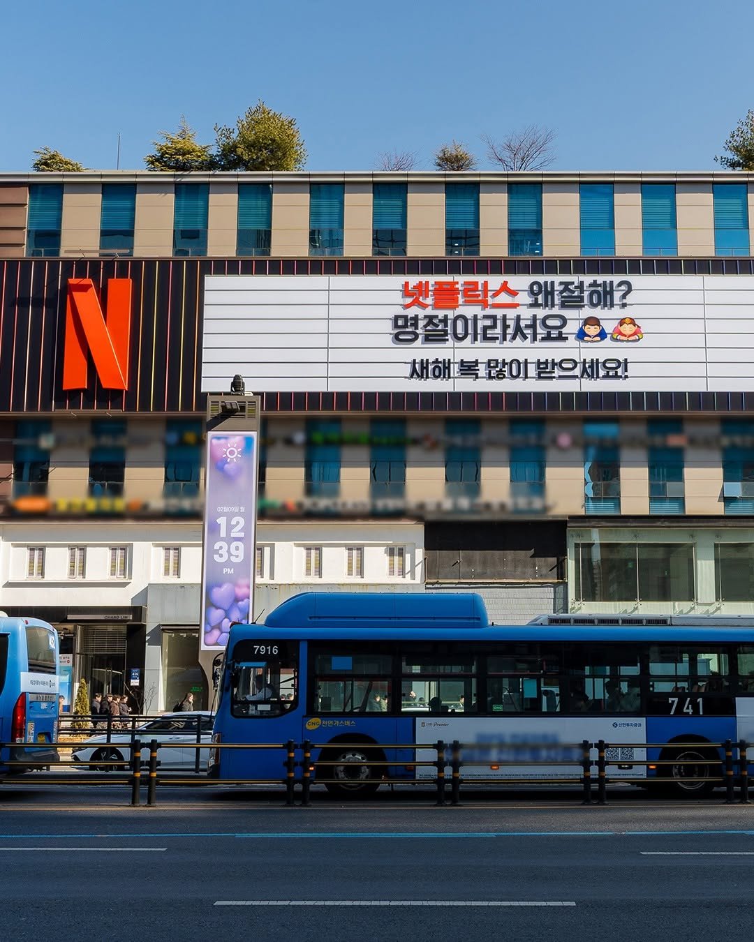 Photo by Netflix Korea | 넷플릭스 코리아 on February 16, 2026. May be an image of one or more people, bus, signboard, street, buildings and text.