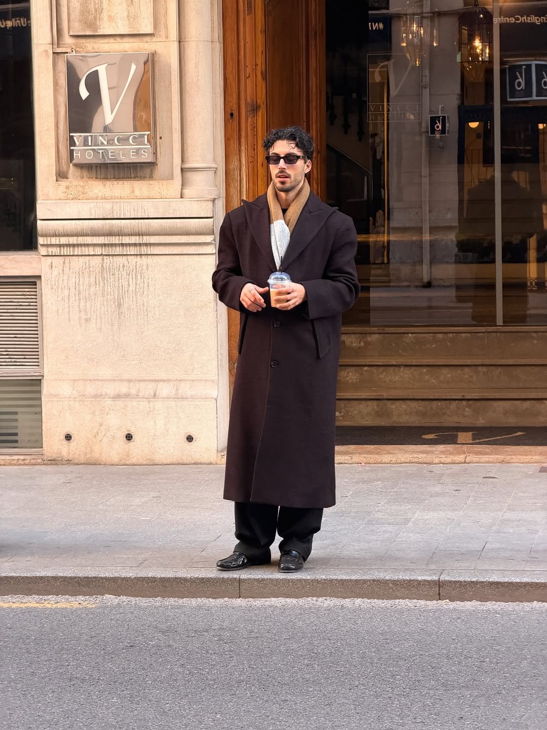 Photo by Nico on December 02, 2025. May be an image of one or more people, people smoking, people standing, overcoat, duffle coat, headscarf, bowler hat, cigarette, street and text.