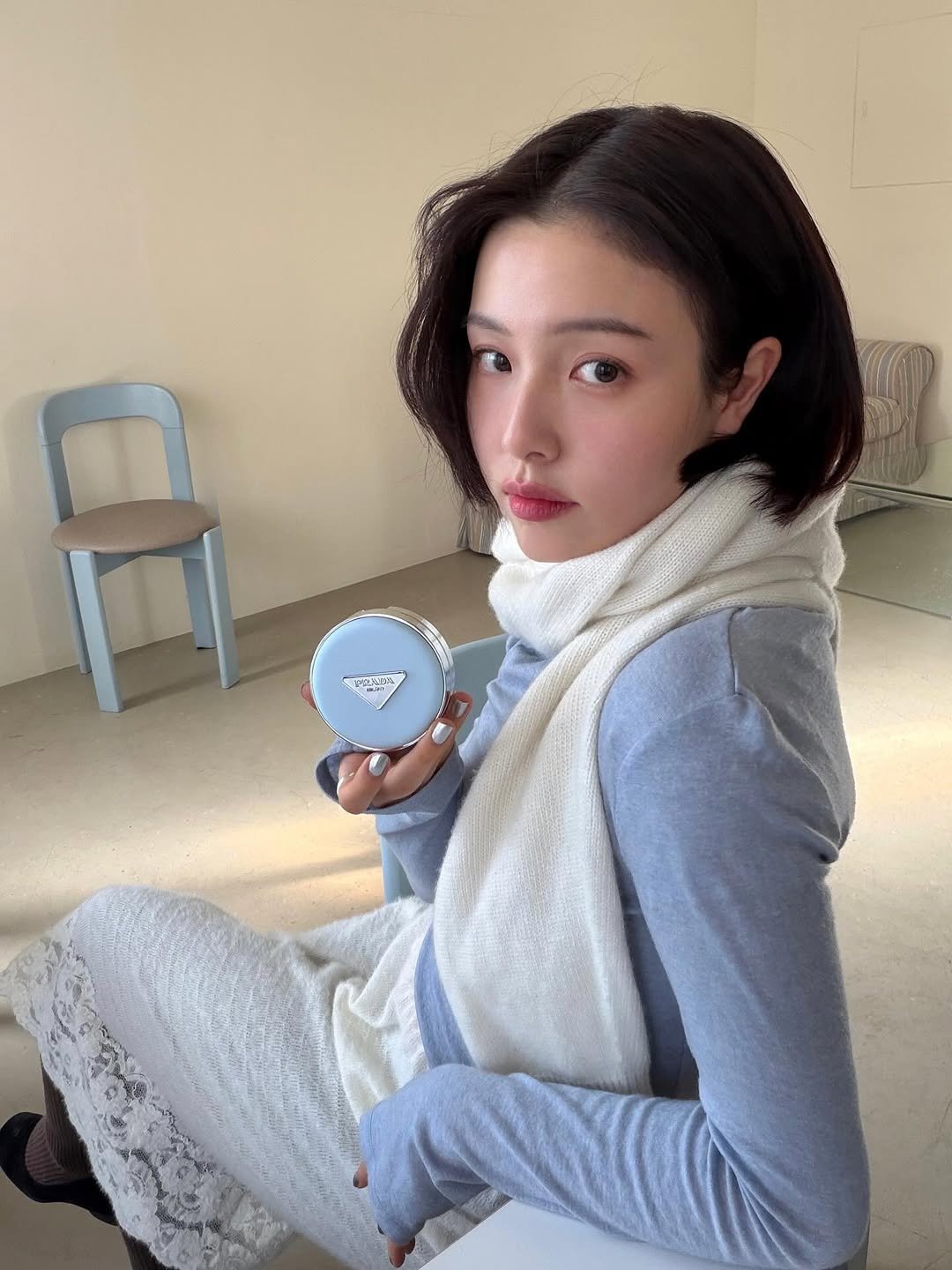 Photo shared by Ga Young on January 02, 2026 tagging @pradabeauty. May be an image of one or more people, hair, makeup, phone, turtleneck, bath robe, cornflower and text.