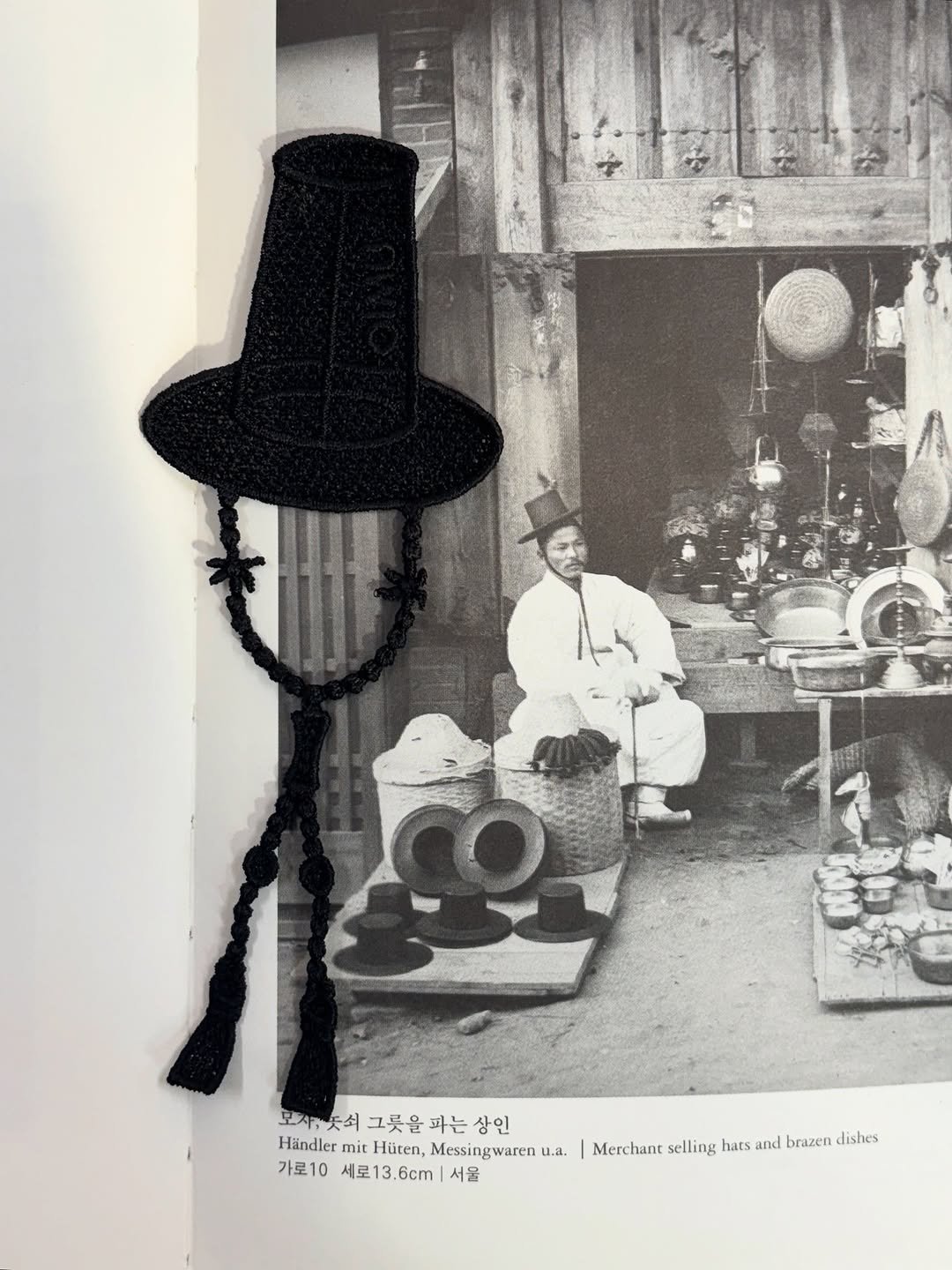 Photo shared by 오이뮤 / OIMU® on November 04, 2025 tagging @oimu_. May be a black-and-white image of bowler hat, newspaper and text that says '모제듯석그릇을과는상인 모지주 보제"듯쇠 그릇을 파는 상인 Händler mit Hüten, Messingwaren U.a. 가로10 세로13 세로13.6cm| 6cm 서물 Merchant selling hats and brazen dishes'.