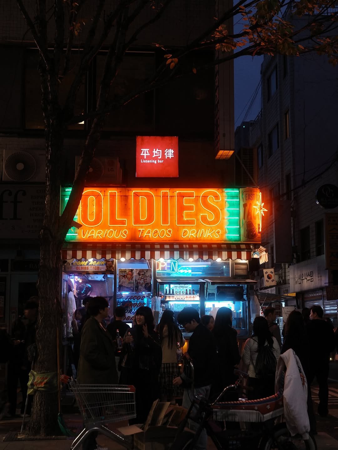 Photo shared by @kai.__.0203 on November 12, 2025 tagging @oldiestaco. May be an image of one or more people, signboard, newsstand, night and text that says 'Lieceming 平均律 Lisconing bar OLDIES VARIOUS TACOS ORINKS Moogdla 00女温 A'.