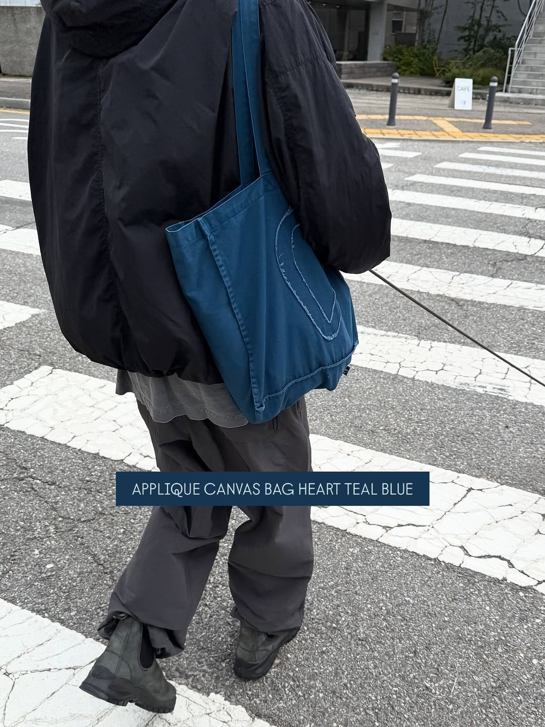 Photo by ooowl on September 29, 2025. May be an image of 1 person, duffle coat, goosedown coat, tool bag, grocery bag, parka, sling and text that says 'APPLIQUE APLIQUECANASBAGHEARTTEALBLUE APPL CANVAS BAG HEART TEAL BLUE'.