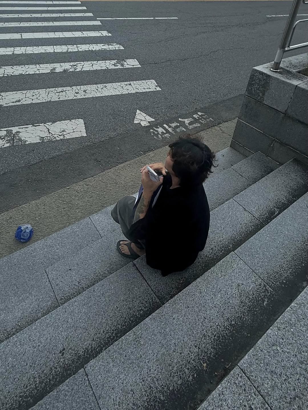 Photo shared by 오윤택/오태기 on August 02, 2025 tagging @ohtaeki_official. May be an image of 1 person, phone, cigarette, street, curb and text.