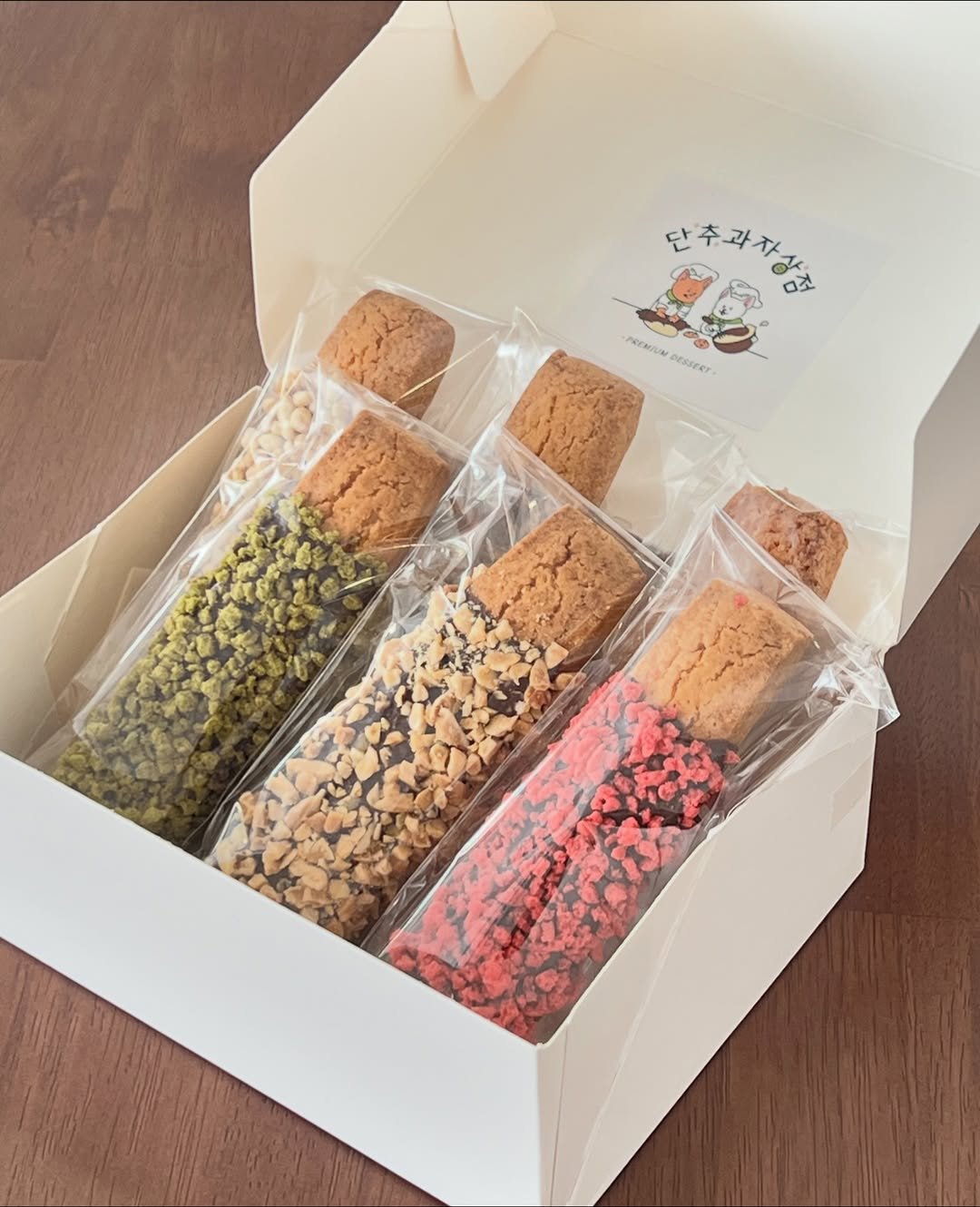 Photo by 단추과자상점 | 청리단길 | 디저트카페 | 다쿠아즈 | 수제디저트 | 두바이쫀득쿠키 on November 08, 2025. May be an image of breadstick, cake, pastry, wafer, hamper and text.