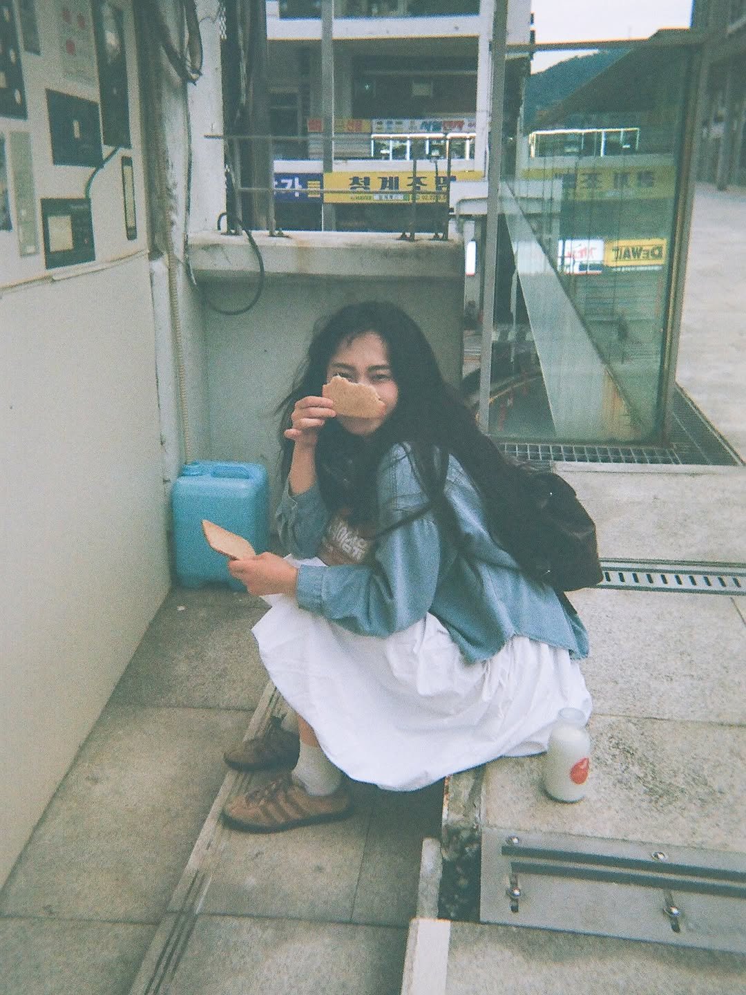 Photo shared by 이선우 on September 07, 2025 tagging @hnapuff. May be an image of 1 person, smoking, phone, cigarette, bus, cornflower, street and text.