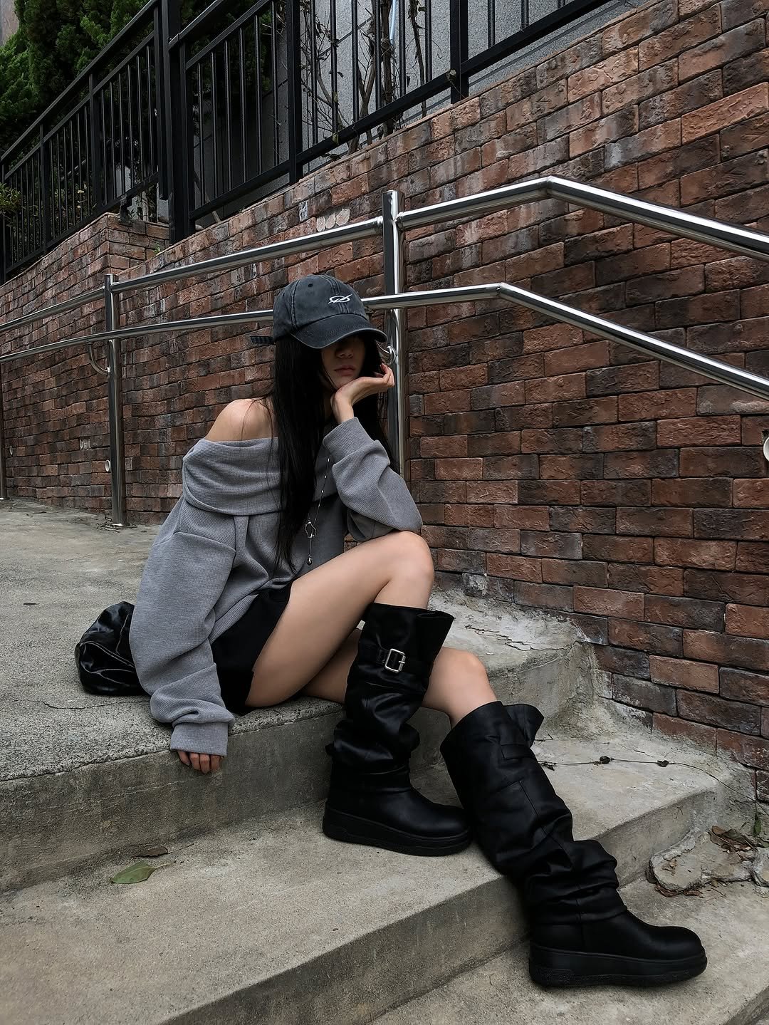 Photo by 피키뚜 on October 09, 2025. May be an image of boots, sweatshirt, miniskirt and brick wall.