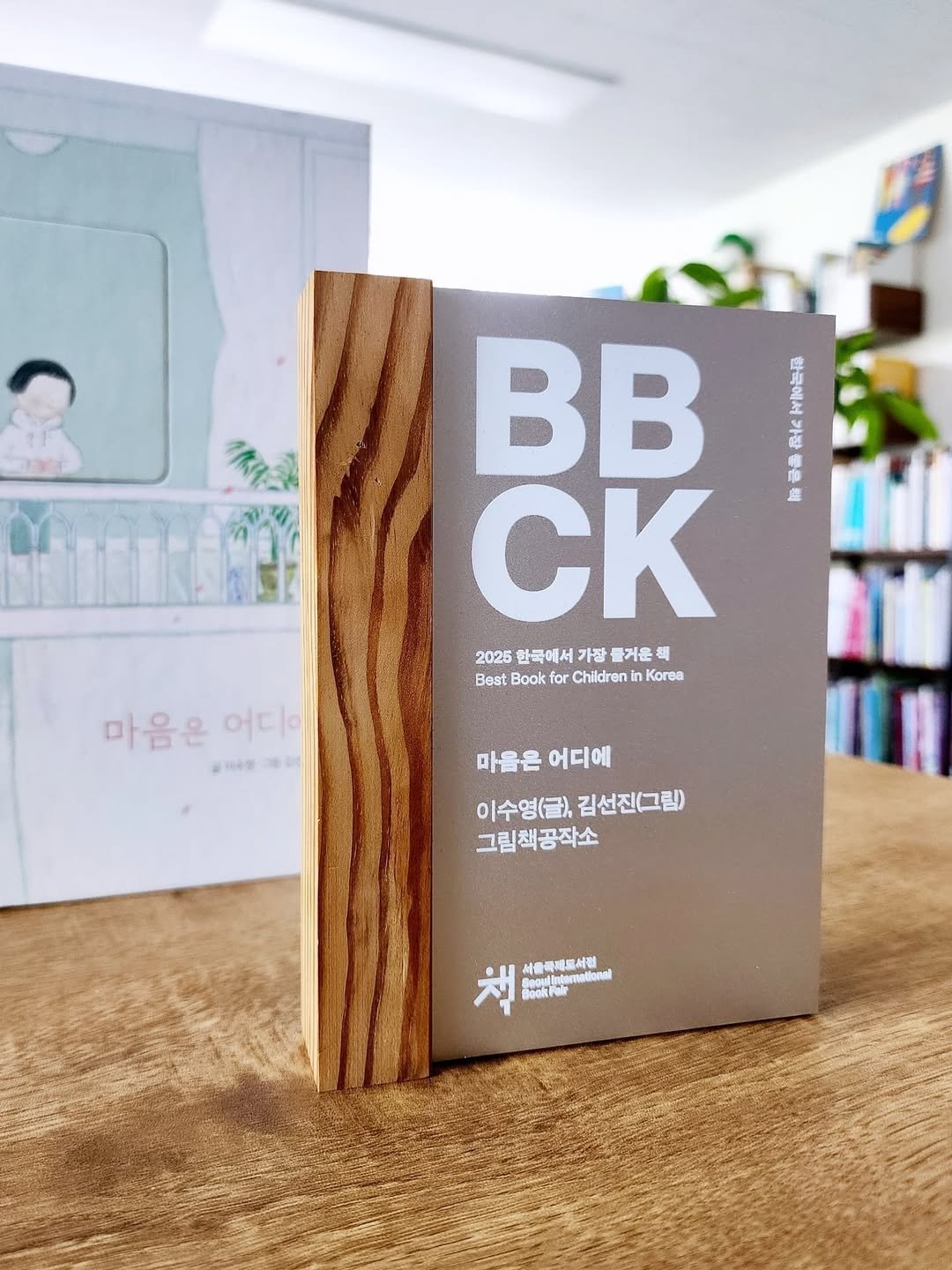 Photo shared by 그림책공작소 on June 19, 2025 tagging @mintplatz_songjiyeon, @o_oharu, @sibf_official, @picturebook_gongjackso, and @hagobooks. May be an image of book and text that says 'BB 七の AR 話 CK 2025 한국에서 가잘 즐거운 2025만국에서가장즐거운식 鶴 Best Book for Children inK Korea 마음은어디이 어디. 마음은 204ง a0g De0m 마을은어디에 마을은 어디에 이수영(글), 김선진(그림) 그림책공작소 책 BookPo 서울국세르세럼'.