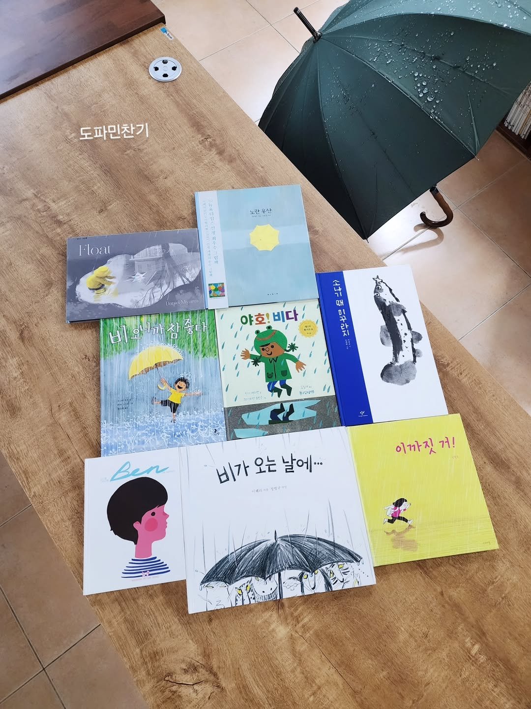 Photo shared by 그림책공작소 on April 09, 2026 tagging @picturebook_gongjackso. May be an illustration of book, umbrella, card, parasol and text that says '도파민찬기 노란봉산 Float 仕けご 야호! 야호!비다 비다 Ben 비가오는날에... 비가 오는 날에... บุสเจ 남이다 di-o 이까짓거! 거! 이까짓거'.