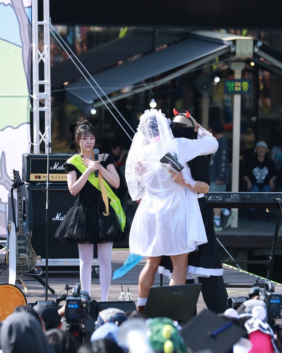 Photo by QWER on April 20, 2026. May be an image of one or more people, parasol, costume, tambourine, crowd, concert and text that says '영업중 Mar · N Ce Ma ES ほだ'.