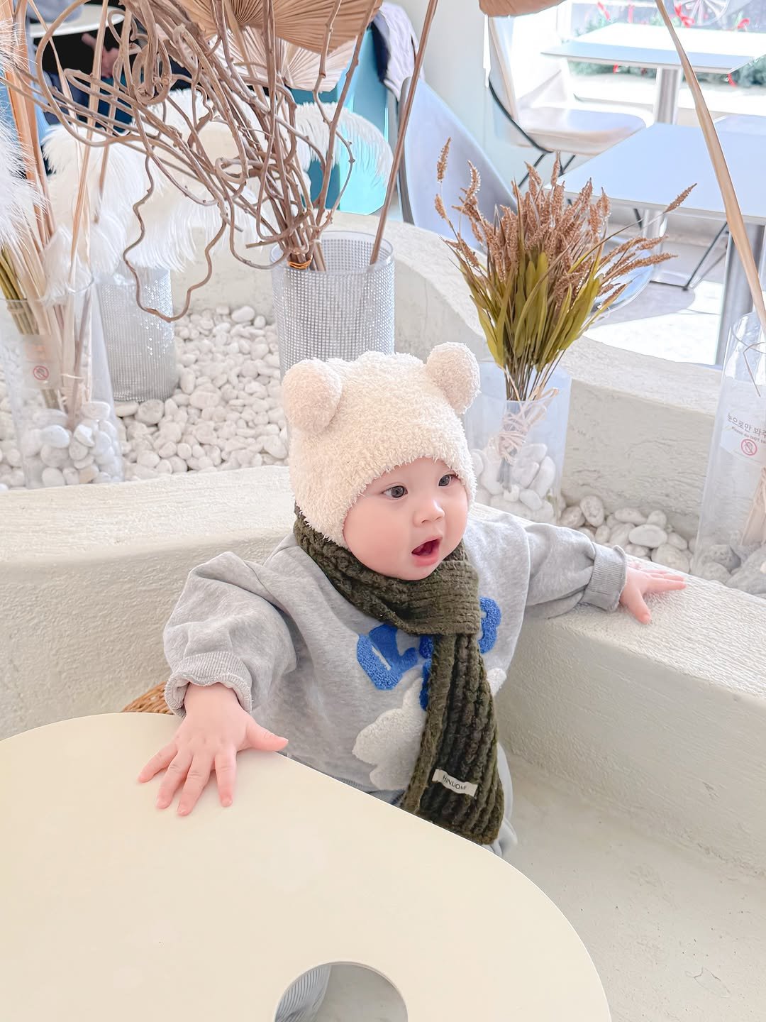 Photo by 1일1도하🖤 on March 02, 2026. May be an image of baby, standing, bear, duffle coat, hat and text.