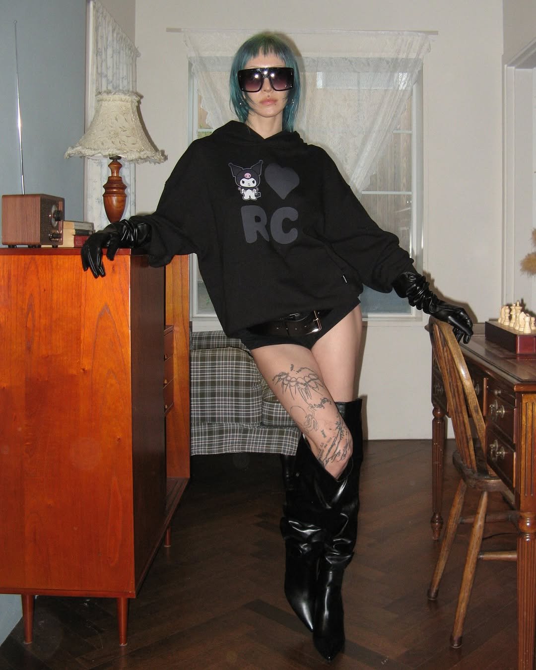 Photo shared by ROCKCAKE on December 19, 2025 tagging @sanrio, @musinsa.official, and @sanrio_kr. May be an image of boots, sweatshirt, glasses, fishnet stockings, miniskirt, eye patch and text.