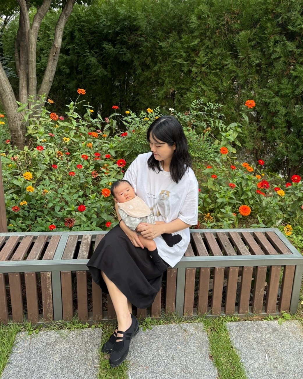 Photo by 새미 on October 19, 2025. May be an image of baby, sling, flower, outdoors and text.
