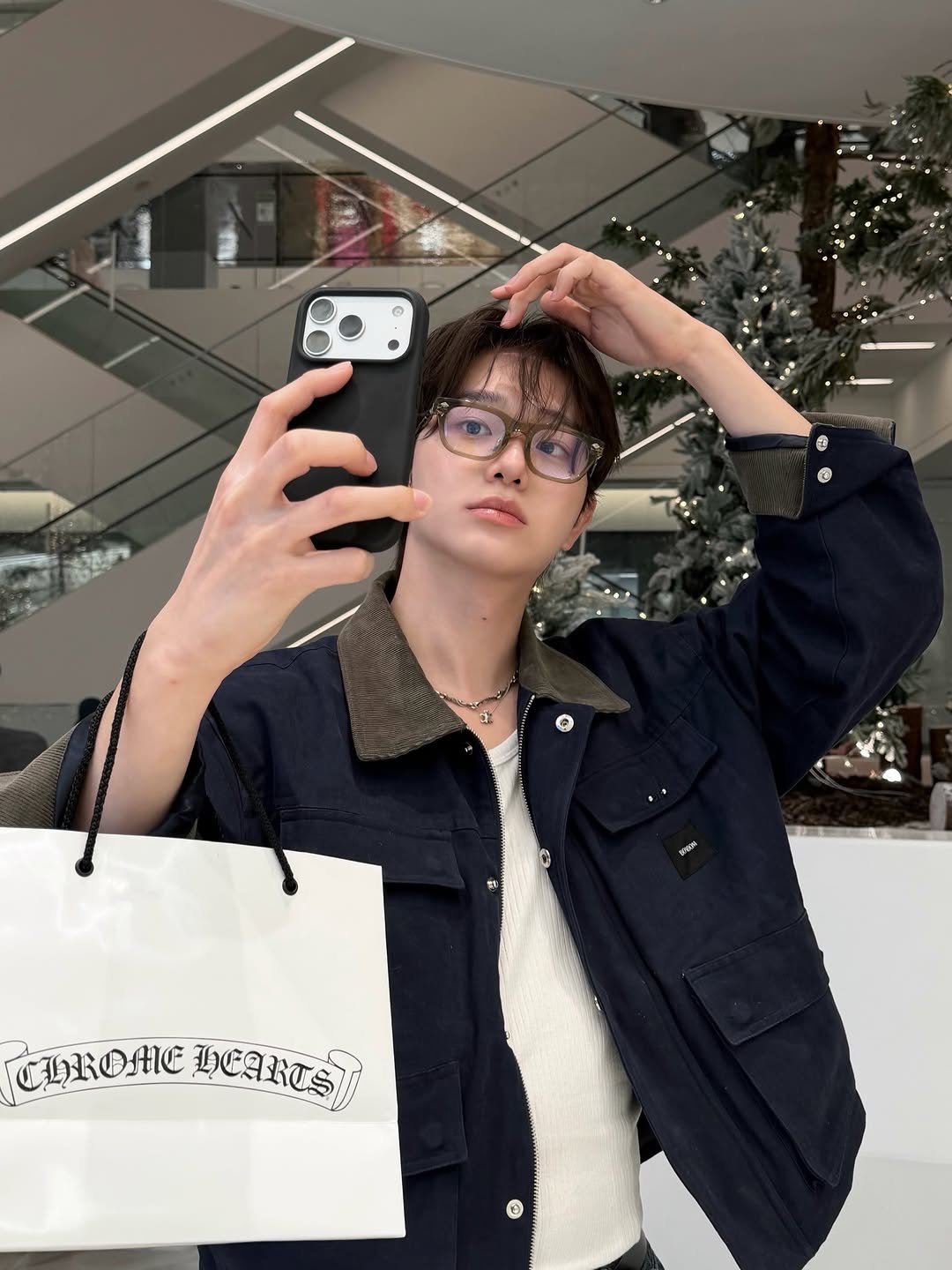 Photo shared by 서눙 on December 29, 2025 tagging @chromeheartsofficial, @__bonbom, and @thehyundai_seoul. May be a selfie of duffle coat, phone, eyeglasses, mirror, clothes hanger, jacket, cornflower and text.