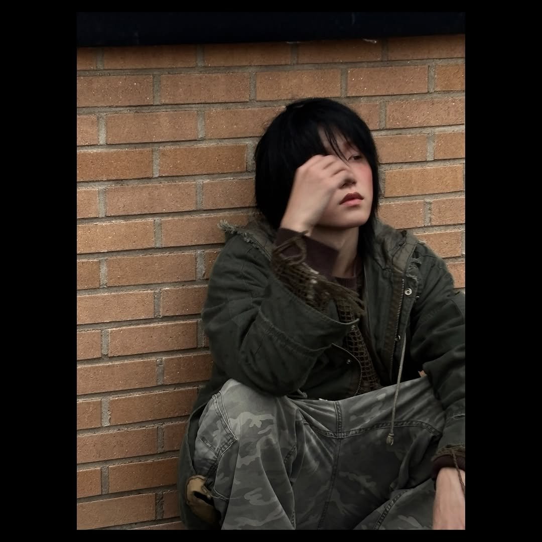 Photo by JONGSEOB on March 09, 2026. May be an image of duffle coat, cigarette, military uniform, parka, jacket, brick wall and text.