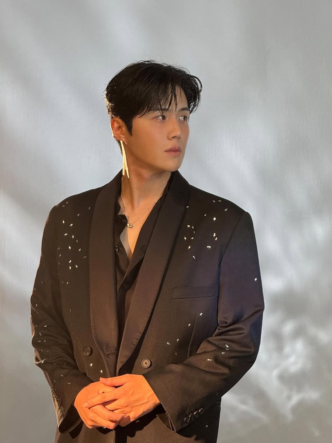 Photo by 김선호 on November 14, 2025. May be an image of one or more people, bangs, makeup, bolo tie, blazer, dinner jacket, suit and text.