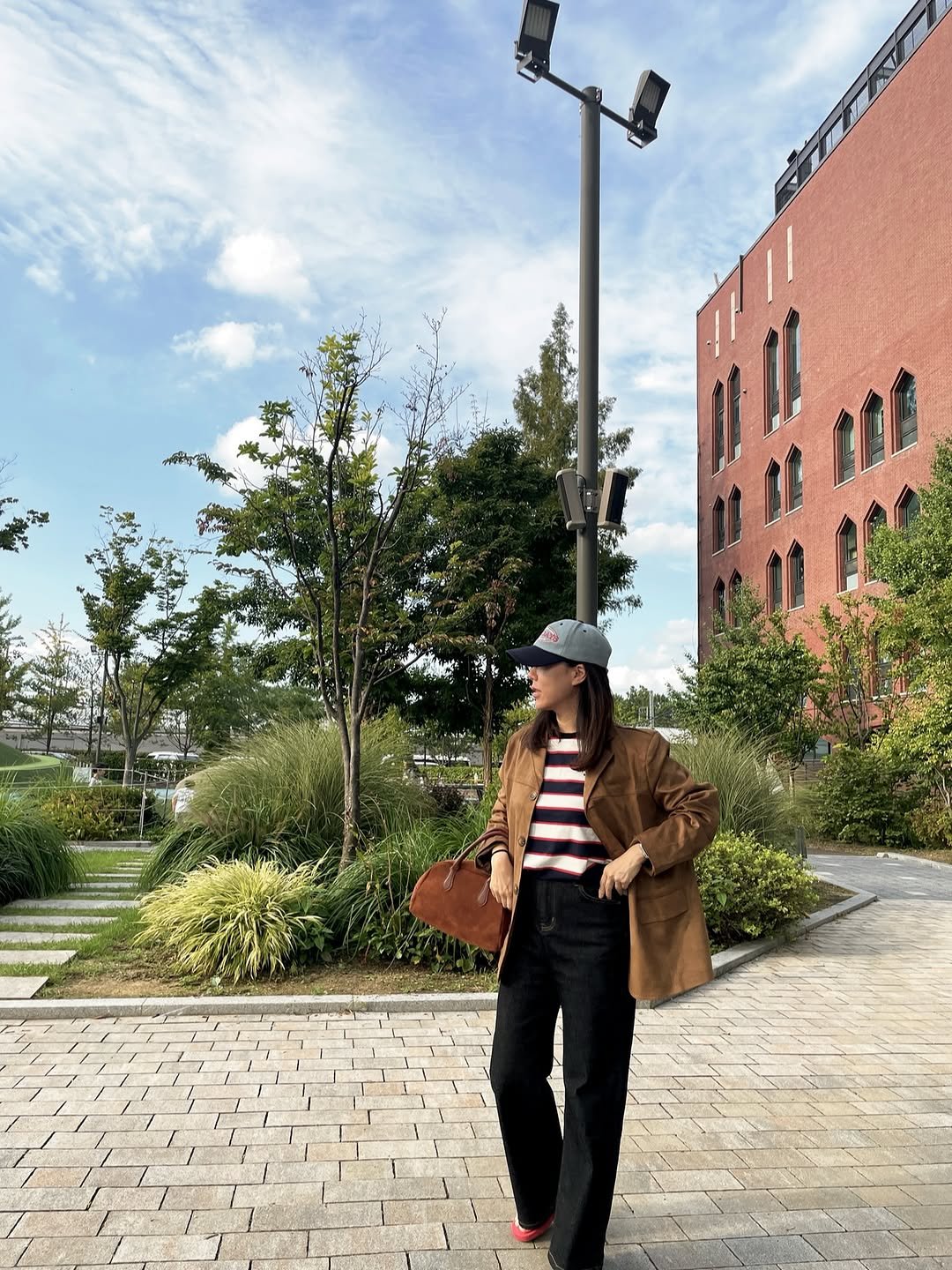 Photo by sera jung on September 24, 2025. May be an image of 1 person, overcoat, duffle coat, bowler hat, street, lamppost and text.