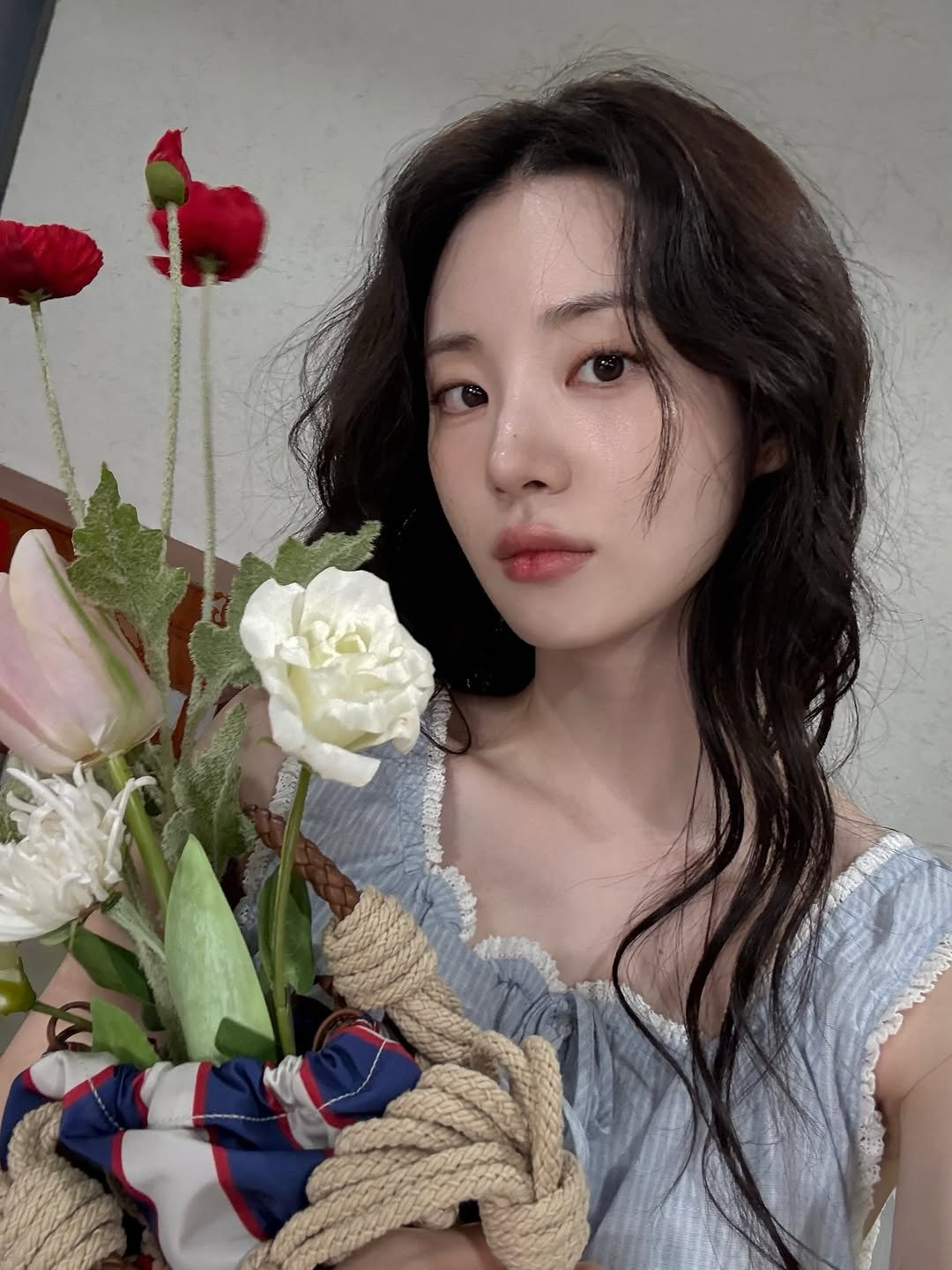 Photo shared by 신시아 on July 30, 2025 tagging @prada. May be an image of 1 person, hair, baby's-breath, white lily, prairie gentian, rose and text.