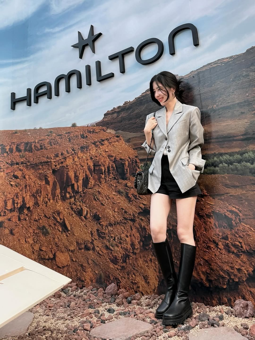 Photo shared by Eunbi Kim on September 11, 2025 tagging @hamiltonwatch. May be an image of 1 person, standing, pants, miniskirt, blazer, boots and text that says 'HAMILTON HAMILTON'.