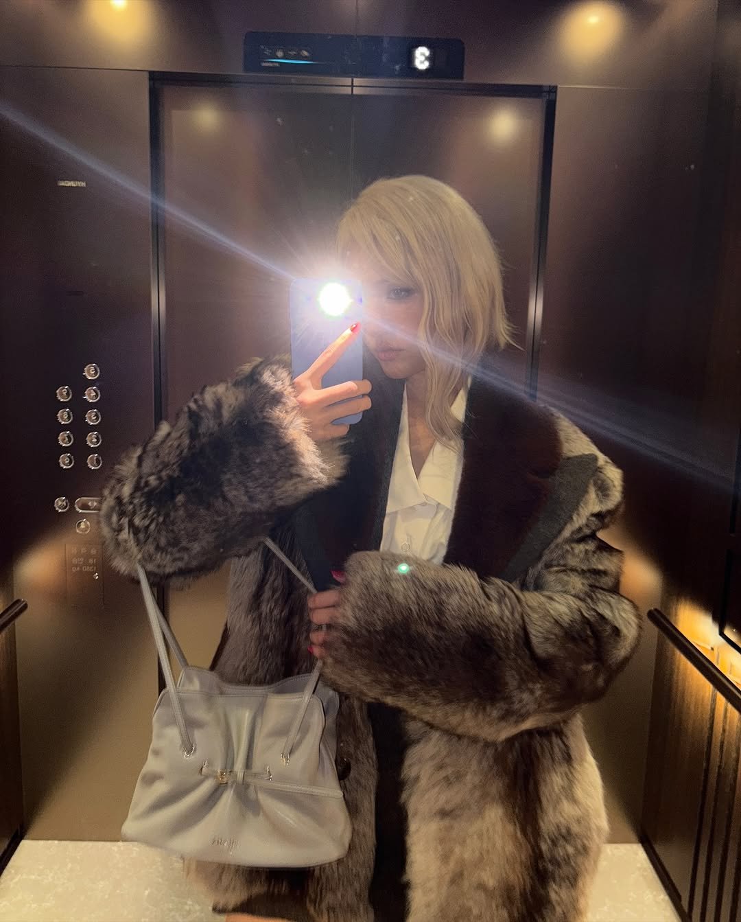 Photo by SOMI on October 15, 2025. May be a selfie of one or more people, blonde hair, sable coat, duffle coat, overcoat, parka and text.