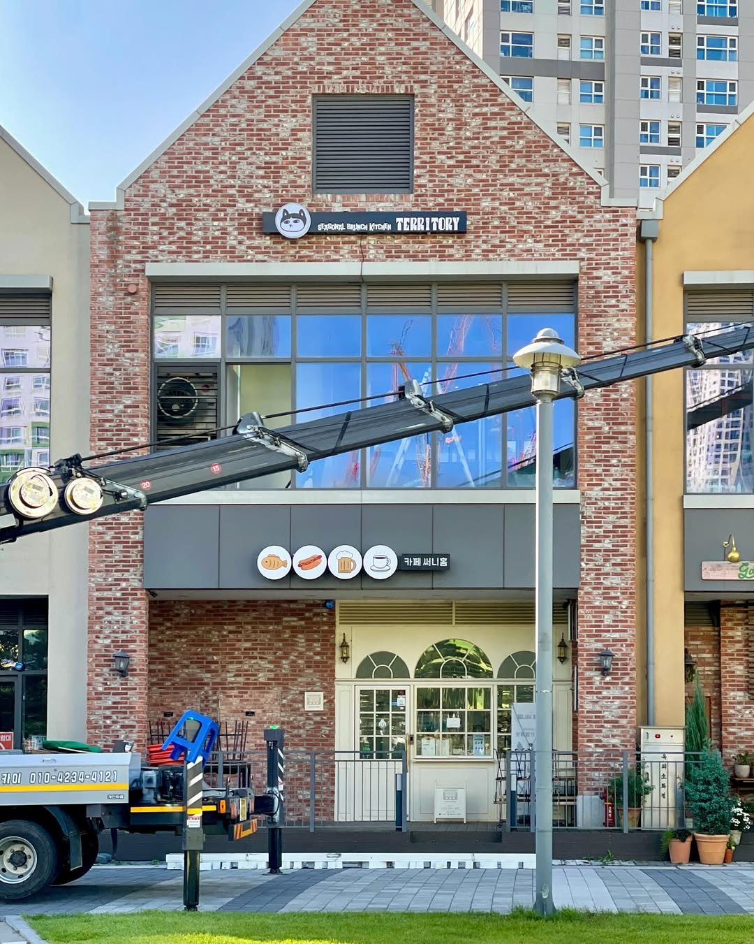 Photo shared by 송도 브런치 카페 테리토리 on December 31, 2025 tagging @territory_official_, and @vegetory_lab. May be an image of signboard, crane, lamppost, brick wall, buildings and text.