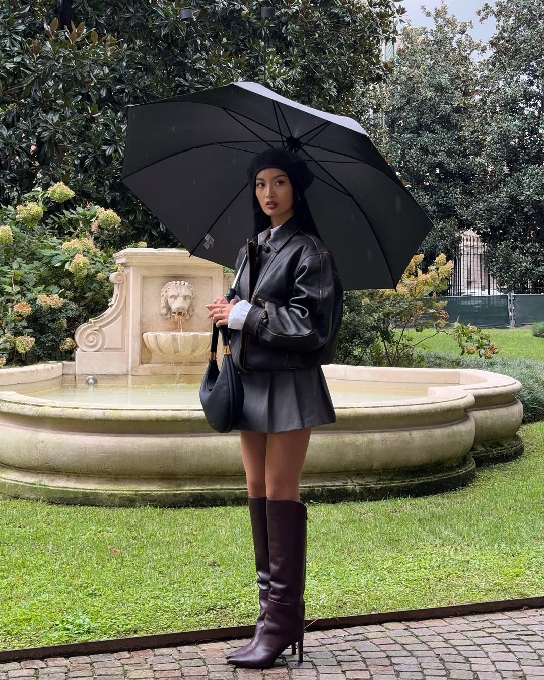 Photo by Thanya Wong on September 27, 2025. May be an image of 1 person, boots, overcoat, umbrella, parasol, miniskirt and text.