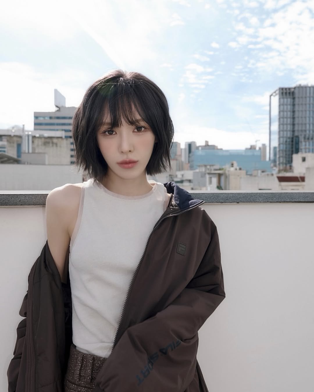 Photo shared by Wendy on October 10, 2025 tagging @youuu_o2, and @fila_korea. May be an image of one or more people, hair, duffle coat, jacket, top, parka and text.