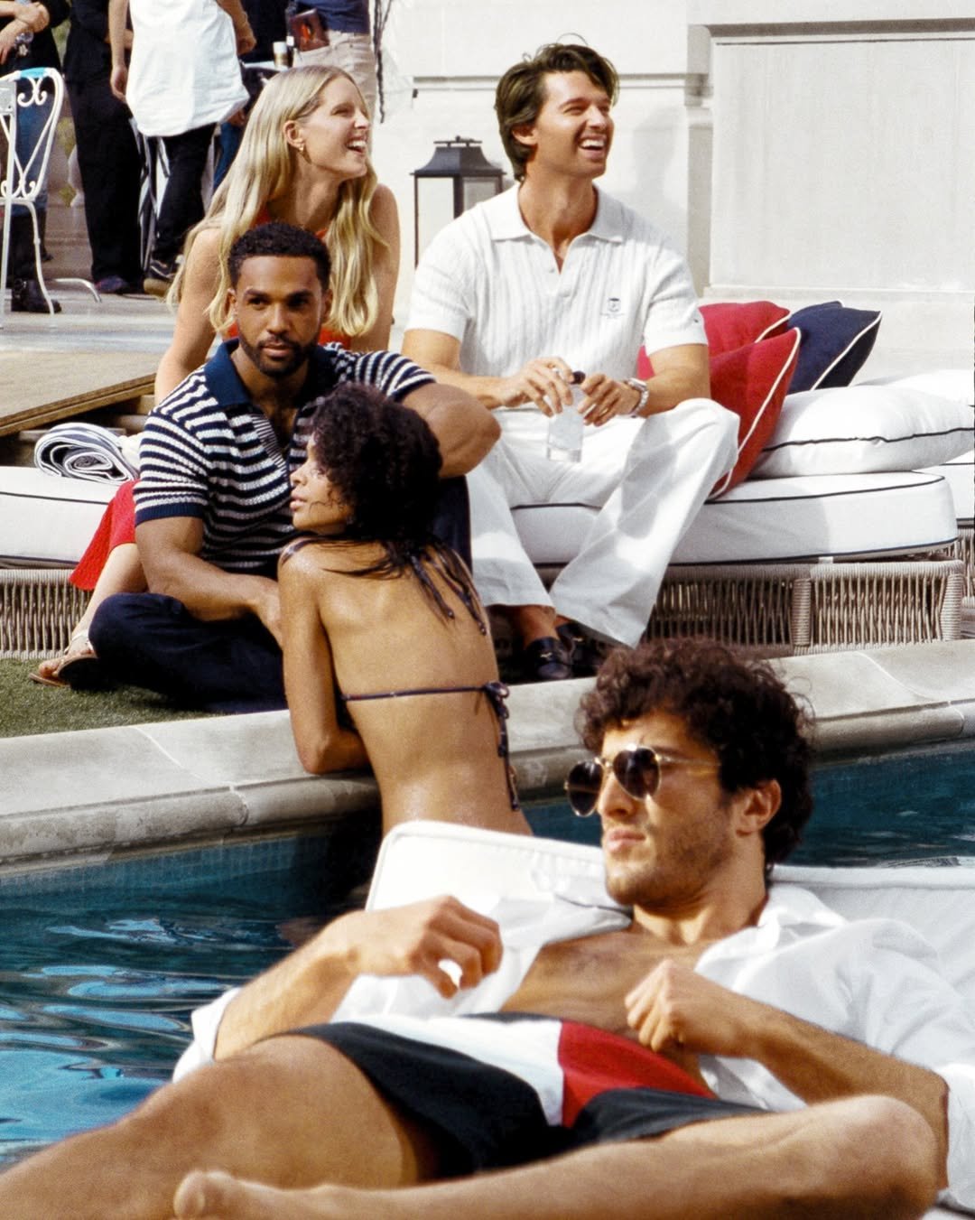 Photo shared by Tommy Hilfiger on April 02, 2026 tagging @patrickschwarzenegger, @abbychampion, @its_lucien, and @_raphaaaa. May be an image of deck chair, chaise lounge, cabana and text.