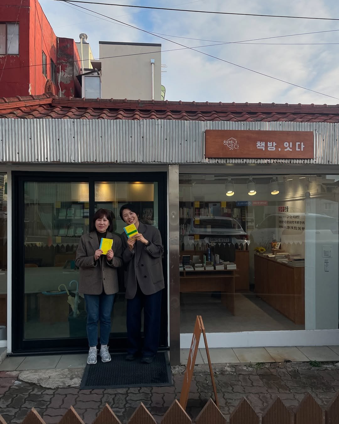 Photo shared by 터틀넥프레스 on April 22, 2025 tagging @itda.bookstore. May be an image of 2 people, duffle coat, display case, cornflower, telephone pole and text.