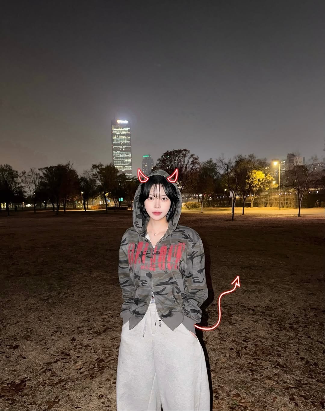 Photo shared by 유빈 on November 24, 2025 tagging @idws_official. May be an image of cloak, parka, park and text.