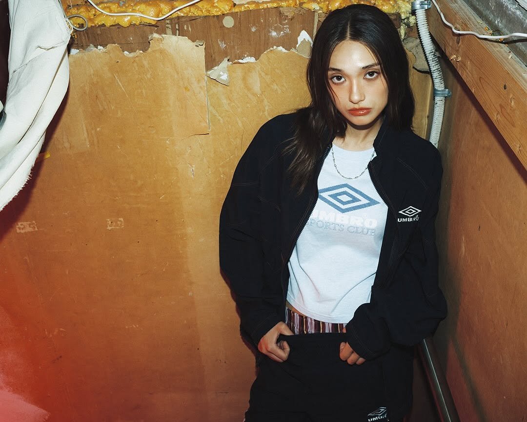 Photo by 엄브로 코리아 on August 21, 2025. May be an image of 1 person, flight jacket, sweatpants, top, sweatshirt and text.