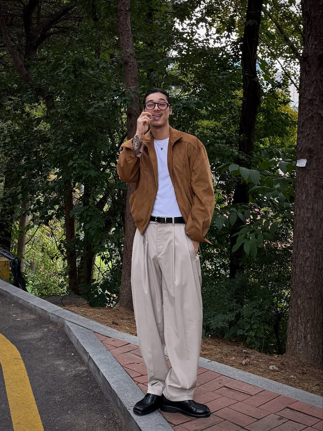 Photo shared by 비 르 on October 23, 2025 tagging @virstyle.kr. May be an image of smoking, wingtip shoes, overcoat, cigarette, cigar, suit, harmonica, portable cassette player, street, curb, park and text.