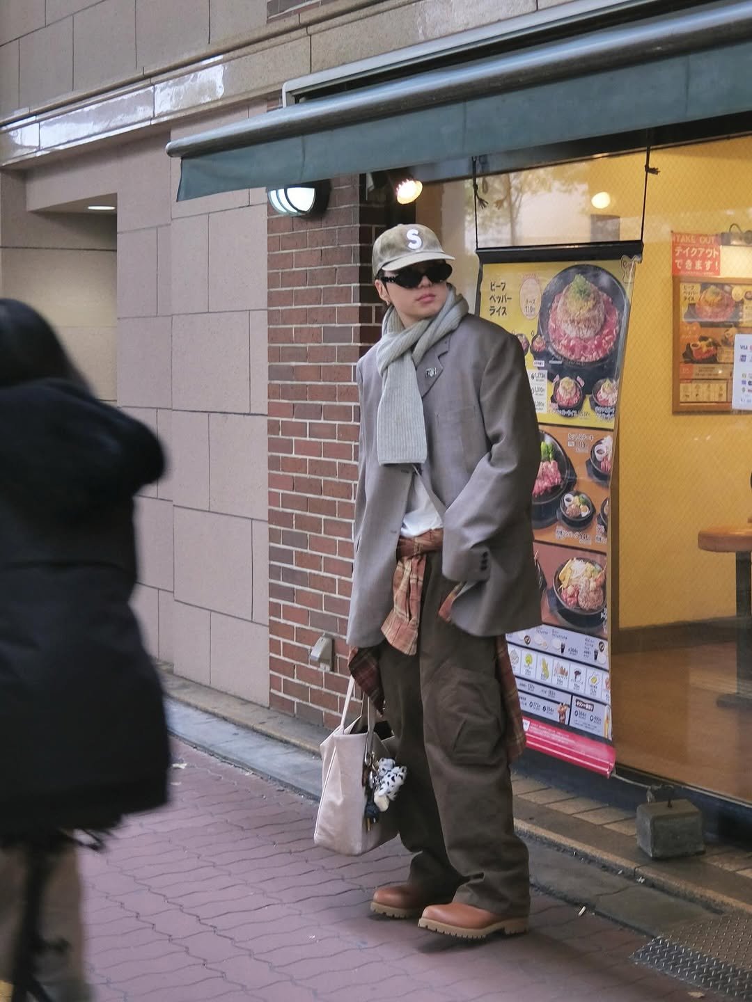 Photo by 강승윤 KANGSEUNGYOON on March 19, 2026. May be an image of one or more people, overcoat, parking meter, duffle coat, parka, street and text that says 'S t-7 สิงที่- ላጎክ ライス テイクアウト1 できます！ 日街 1 0 T ិតជខតា'.