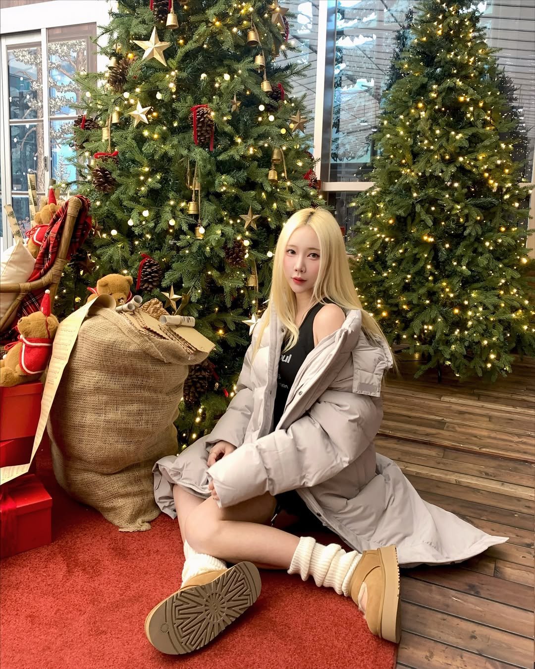 Photo shared by 예린 on November 23, 2025 tagging @fcmm_official. May be an image of one or more people, blonde hair, duffle coat, overcoat, christmas tree, bath robe, parka and text.