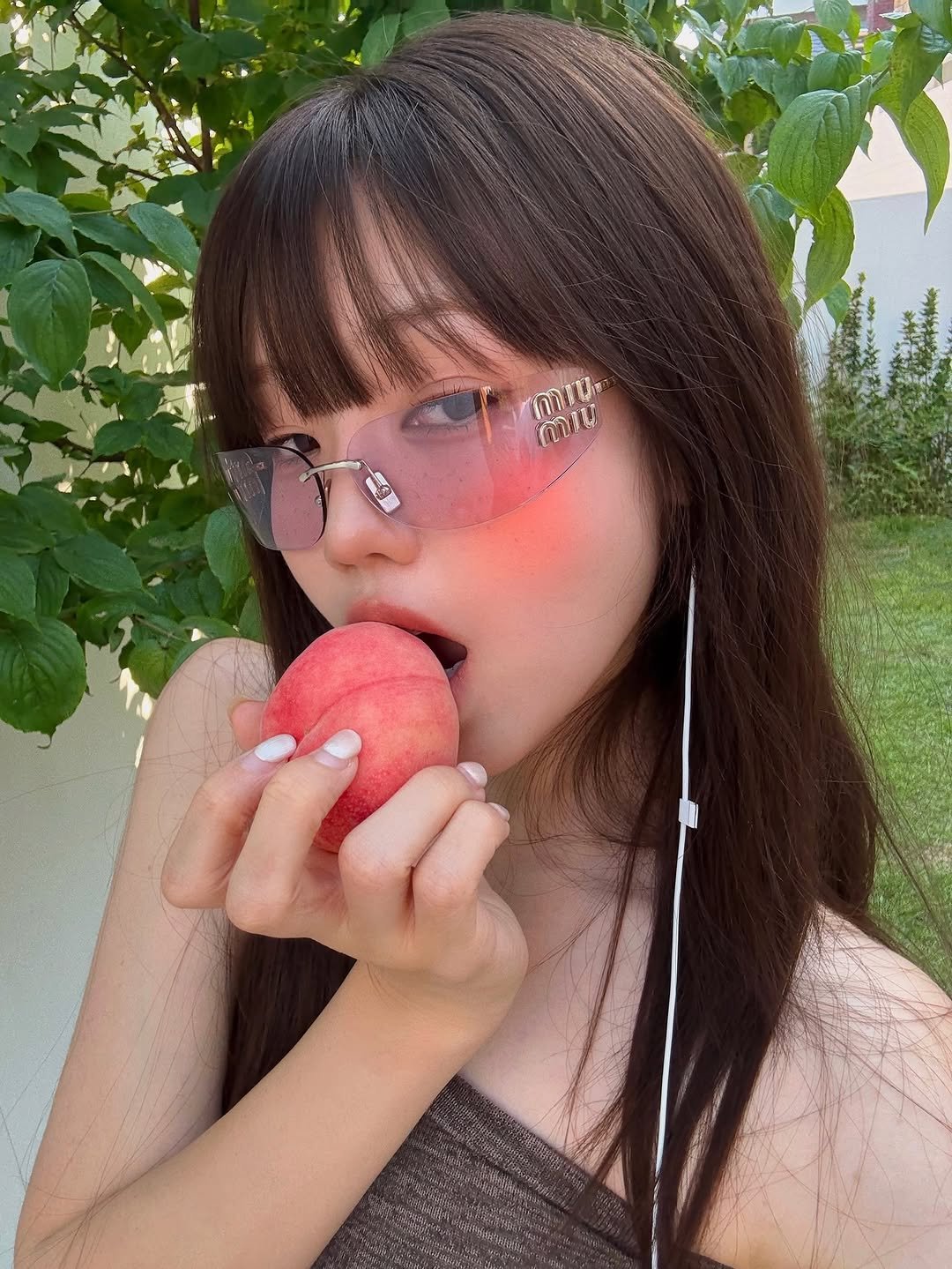 Photo shared by 해삐 on July 13, 2025 tagging @miumiu. May be an image of 1 person, apple and text.