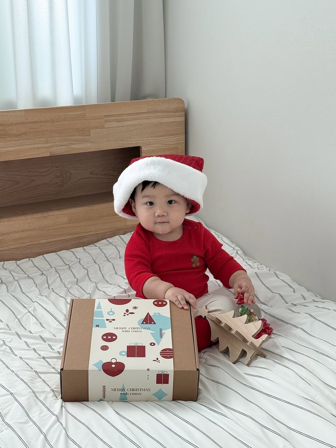 Photo shared by 윤샤샤 ◡̈ on December 25, 2025 tagging @ruuve.official. May be an image of baby, christmas tree, baby bed, carton, box and text.
