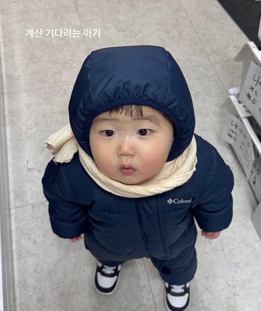 Photo by 김예빈(예블리즈) on February 08, 2026. May be an image of baby, duffle coat, goosedown coat, parka, snowsuit and text that says '계산 기다리는 아기 치즈 Columi oC olumi'.