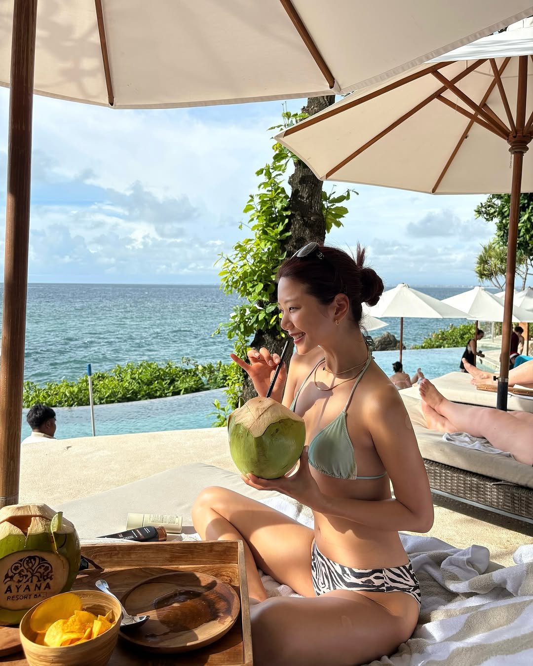 Photo shared by 예지 Yeji 🐿️ KIM on August 07, 2025 tagging @ayanaresort. May be an image of 5 people, coconut, sarong, mangosteen, cabana and text.