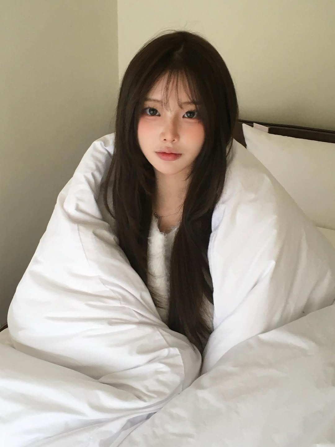 Photo shared by 연 on January 28, 2026 tagging @stay_anyu. May be an image of one or more people, hair, sleepwear, goosedown coat, bed, bath robe, parka, bedroom and text.