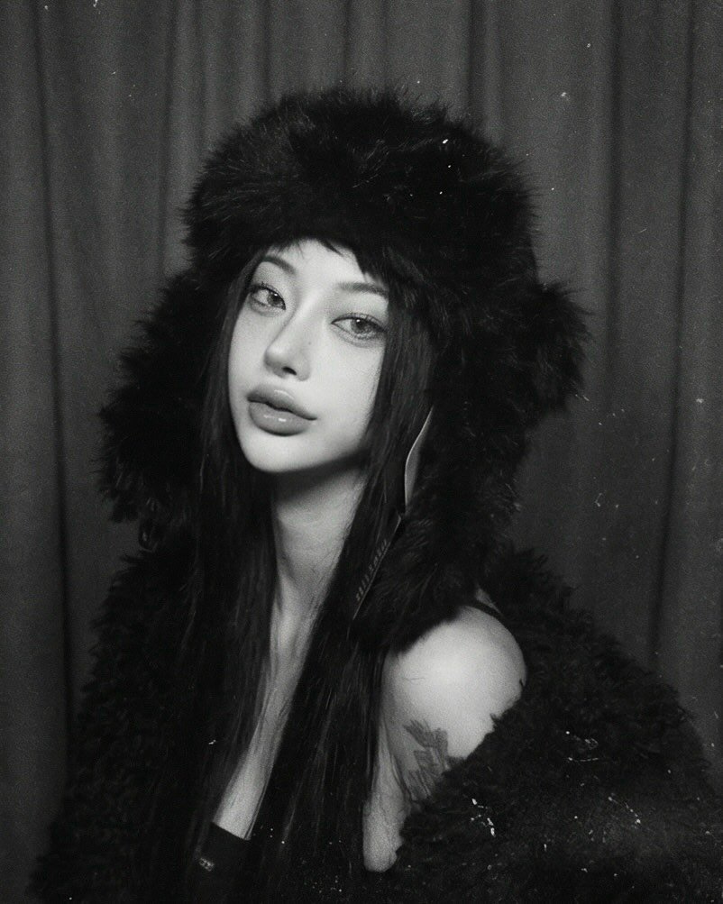 Photo by 선영 on February 10, 2026. May be a black-and-white image of one or more people, makeup, fur coat, hat, cloak, headdress, beret and text.