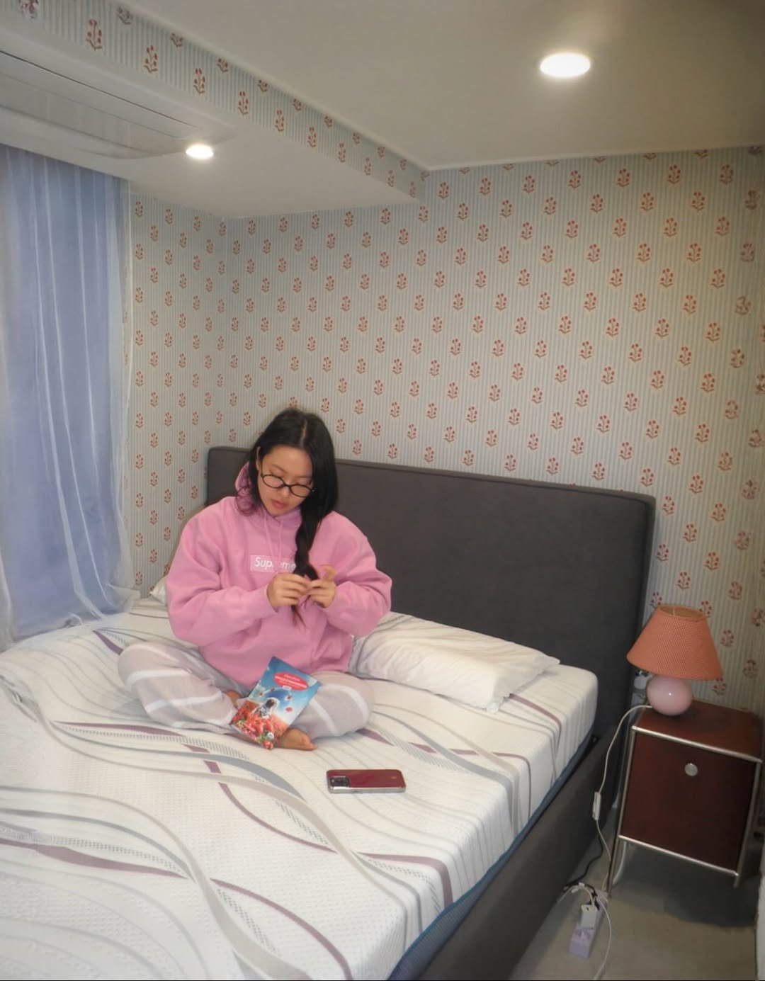 Photo shared by 김예림 🪽 yeri on April 19, 2026 tagging @dorelan_korea. May be an image of phone, sleepwear, bed, bath robe, mattress, headboard, bedroom and text.