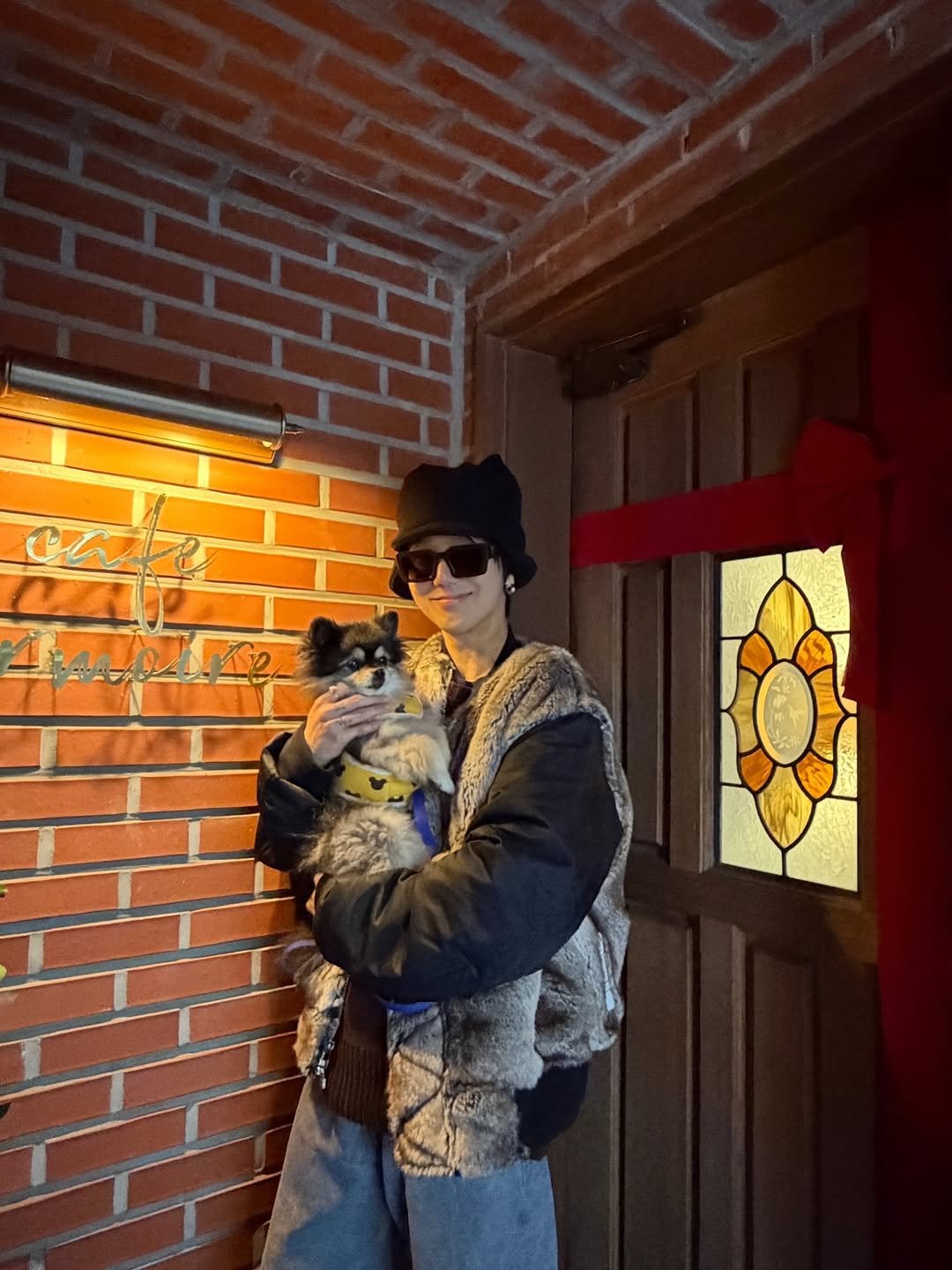 Photo shared by Yesung on December 12, 2025 tagging @cafe_armoire, and @yesung_smtown. May be an image of Bedlington terrier, duffle coat, fur coat, beret, parka, snowsuit, glasses, brick wall and text.