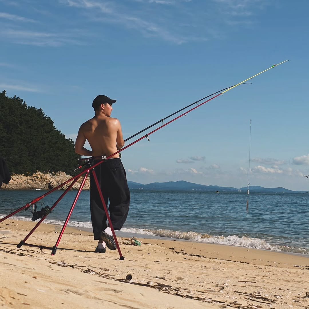 Photo by 요가지몽 on September 21, 2025. May be an image of 1 person, fishing, fishing rod, fish hook, tripod, kite, wetsuit, beach and text.