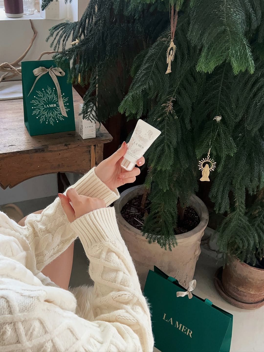 Photo shared by 오늘의 윤세 on November 10, 2025 tagging @lamer.korea. May be an image of christmas tree, sweater, bath robe, perfume, hand cream, lotion and text that says 'MFR- ANIA 九量 i L LA AMIH LAMER AMER MER'.